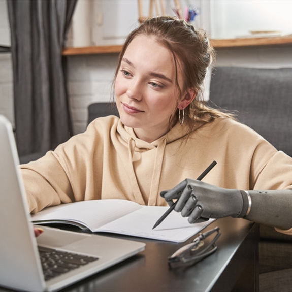Woman with prosthesis arm writing at notebook Woman with prosthesis arm writing at notebook