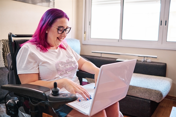 Adult woman with disabilities in a wheelchair working at home with laptop Adult woman with disabilities in a wheelchair working at home with laptop